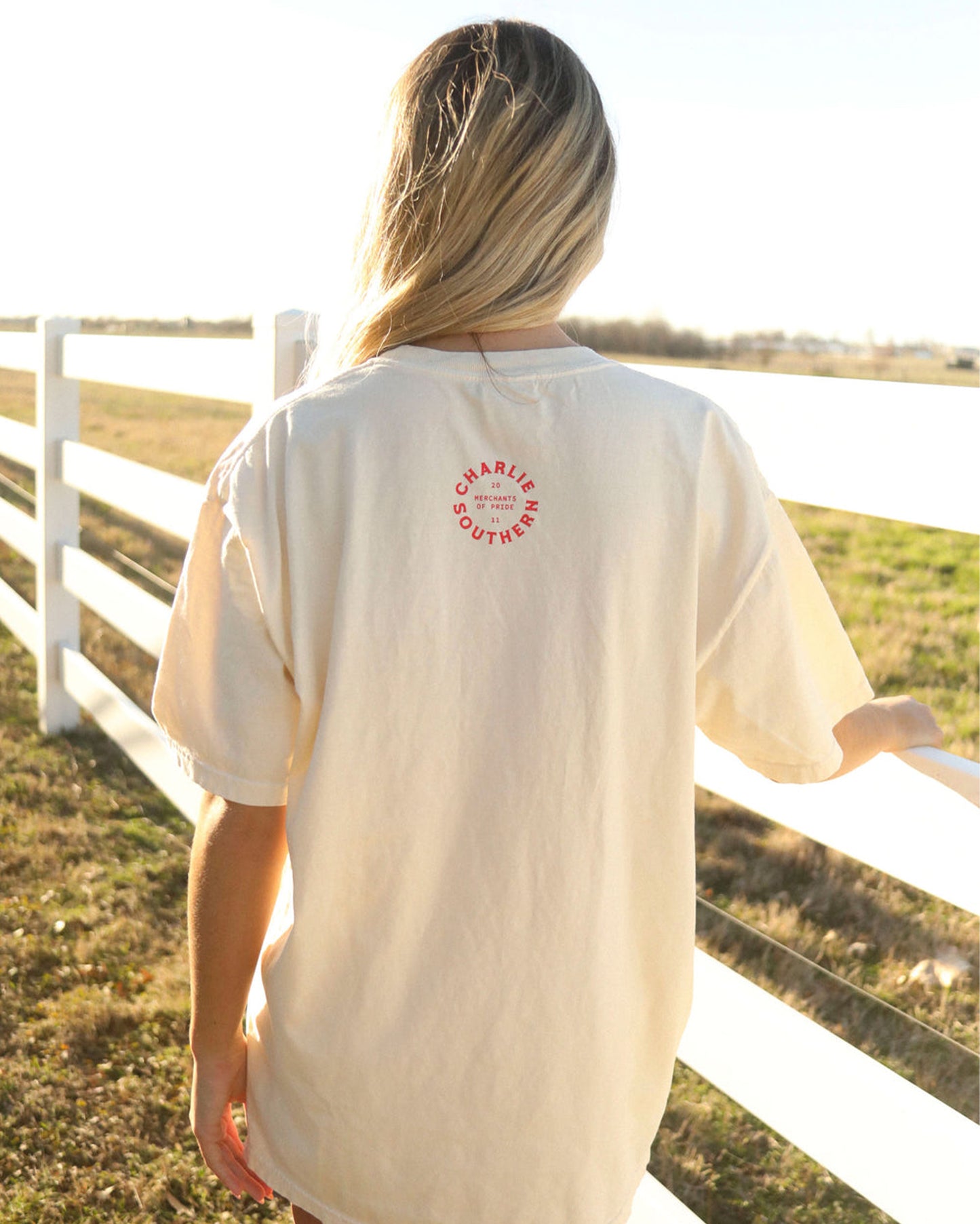 Woman wearing the Women's Cowboy Country Club Martini Tee by Charlie Southern, showcasing a playful design with a large martini and cowboy hat, set against a sunny outdoor backdrop.