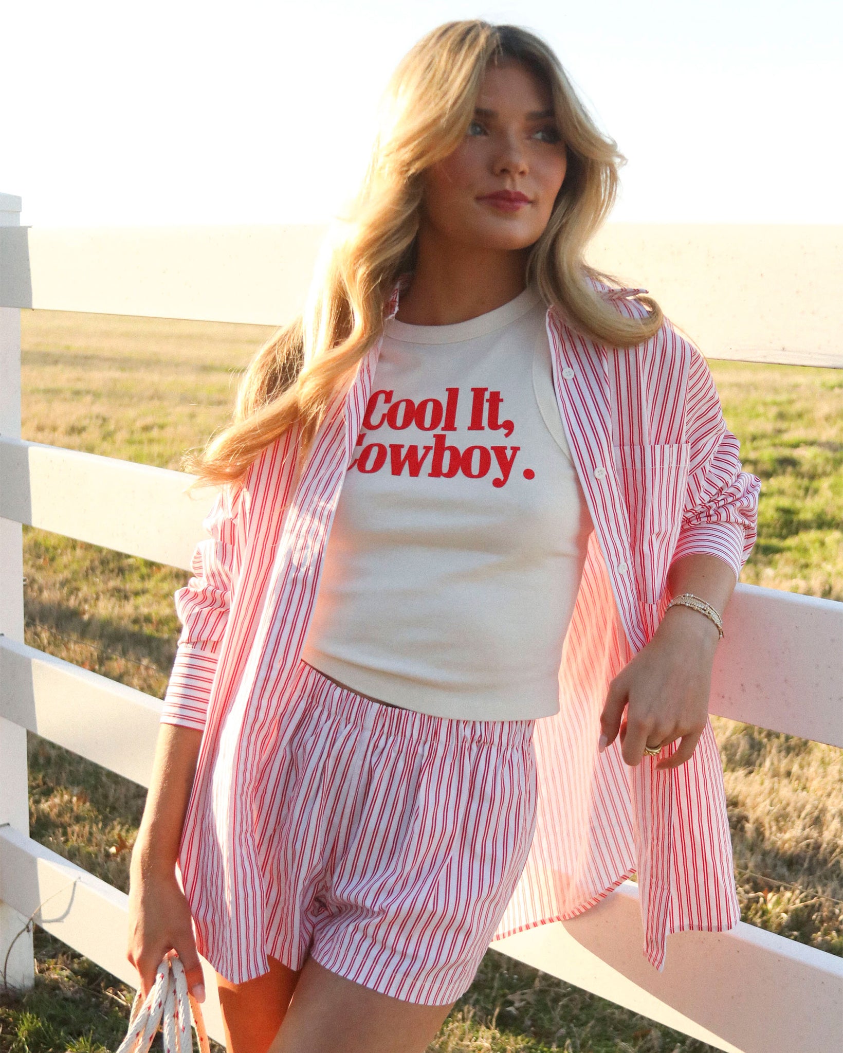 Woman wearing Women's Cool It Cowboy Tank Top by Charlie Southern, styled with a striped shirt and shorts, set against a sunny outdoor backdrop.