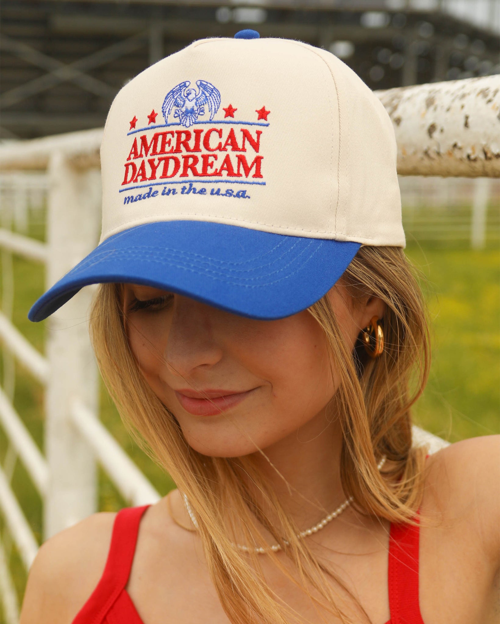 Stylish Women's American Daydream Trucker Cap by Charlie Southern, featuring an off-white front with a royal blue brim, embroidered text, perfect for showcasing the American dream spirit.