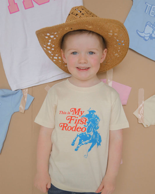 Adorable toddler wearing the 'Not My First Rodeo Tee' by Charlie Southern, showcasing a playful cowboy graphic and bright colors, perfect for little cowboys and cowgirls.